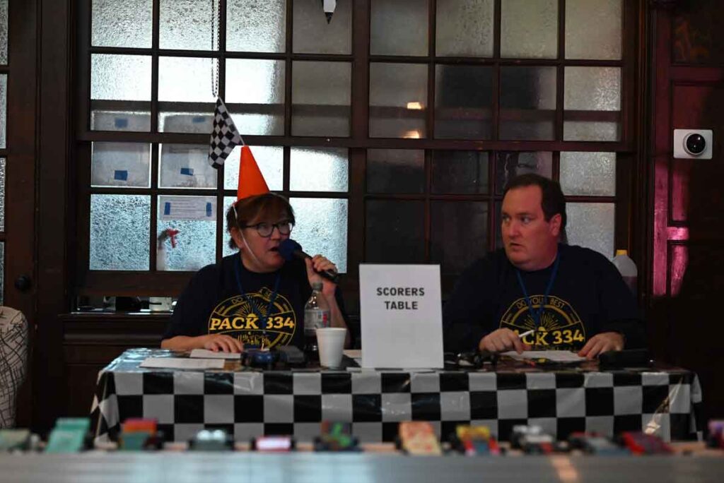 Cub Scout Pack 334 2024 Pinewood Derby Scorers Table with Committee Person Janet McHale and Committee Chair Bill Dunn.